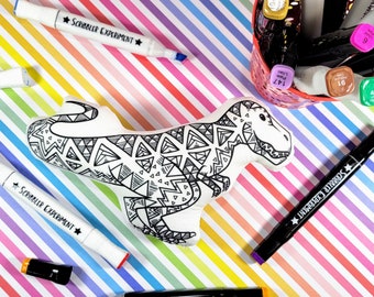 May include: A white plush dinosaur toy with a black and white geometric pattern. The toy is surrounded by colourful markers with the text "Scribbler Experiment" on them.