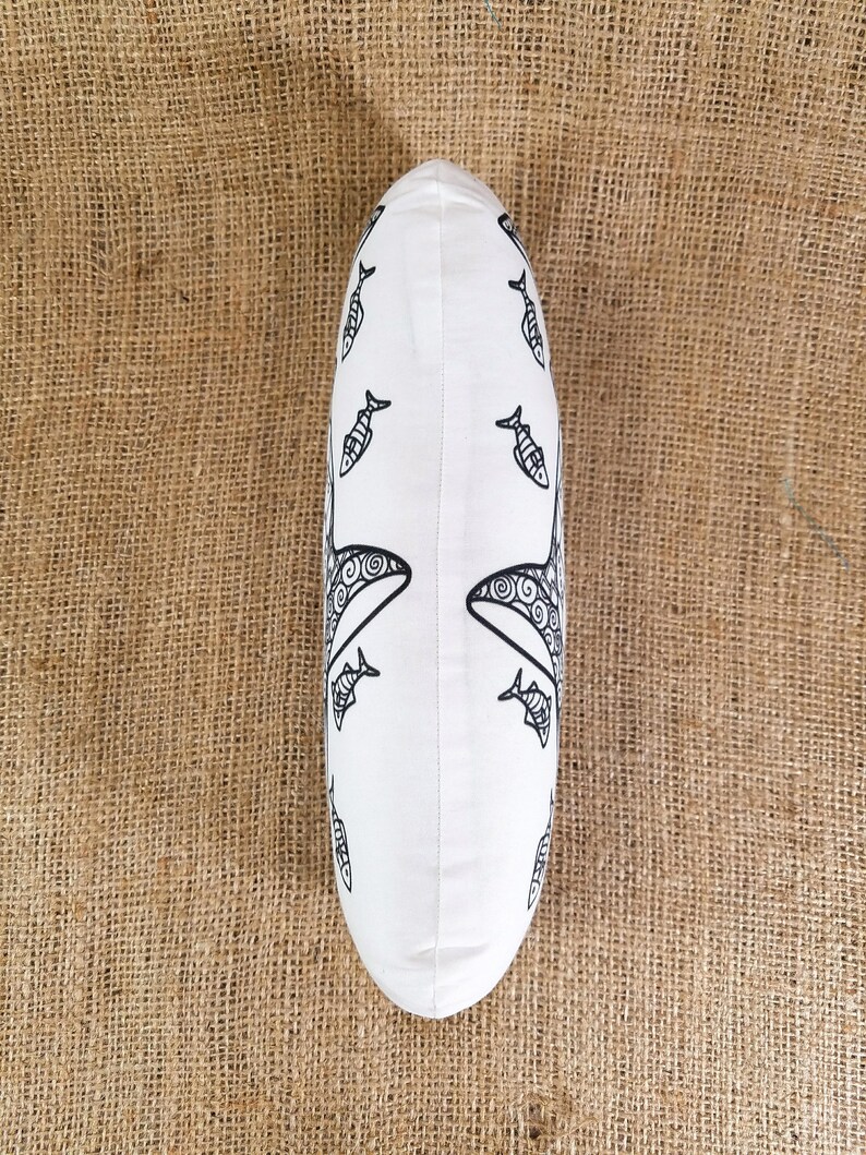 May include: White pillow with a black and white design of fish and whales. The pillow is oval shaped and has a white background.