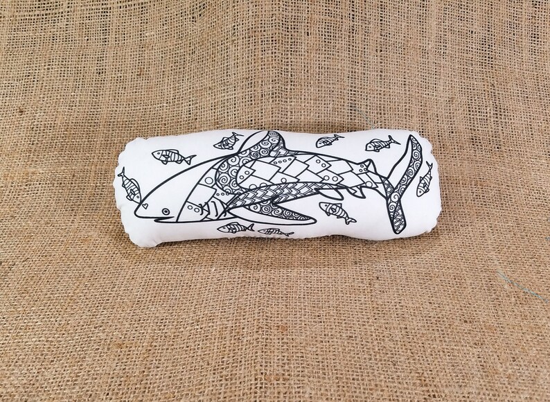 May include: A white pillow with a black and white illustration of a shark with smaller fish around it. The shark is detailed with intricate patterns.
