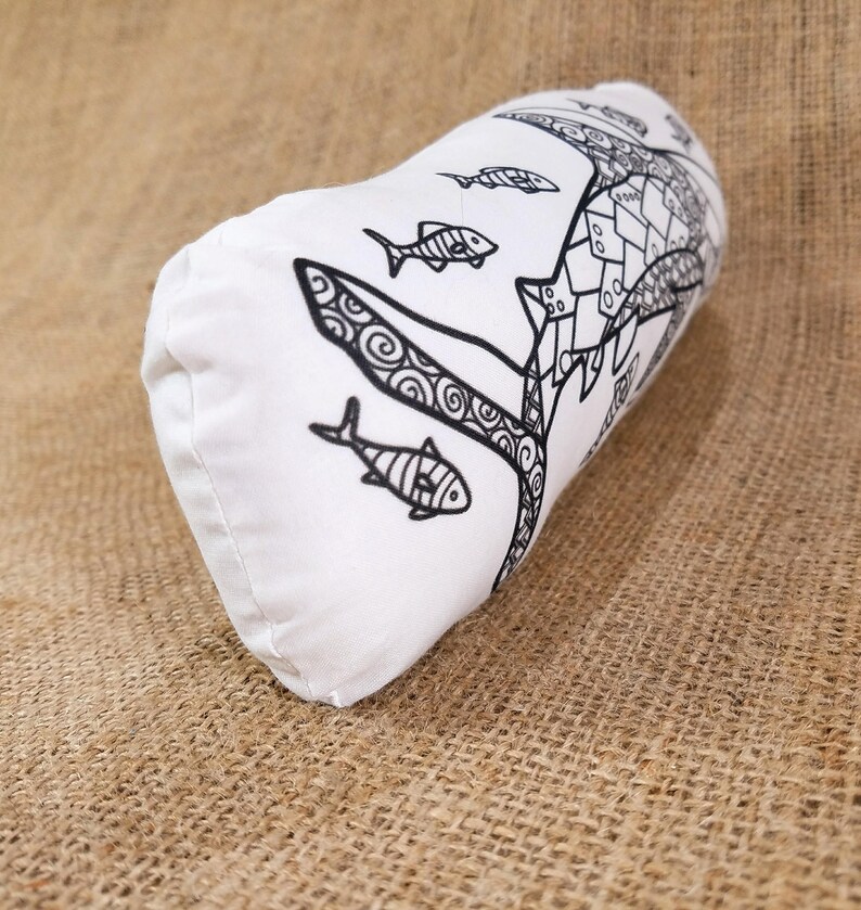 May include: White pillow with a black and white design of a fish with swirls and other fish swimming around it.