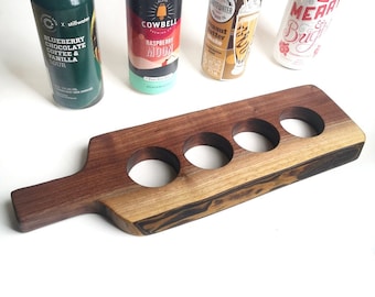 May include: A wooden serving tray with four cutouts for holding cans or bottles. The tray has a dark brown wood finish with black streaks. The tray has a handle on one end.