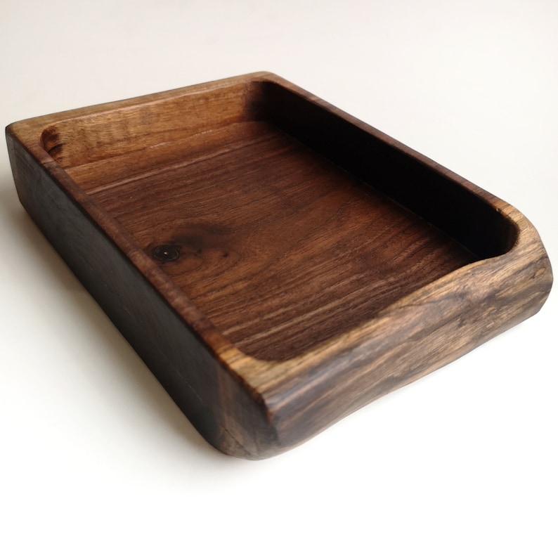 May include: A rectangular wooden tray with a dark brown stain. The tray has a smooth, slightly rounded edge and is made of natural wood.
