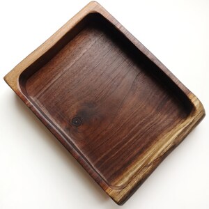 May include: A rectangular wooden tray with a dark brown finish. The tray has a smooth, polished surface and slightly rounded edges.