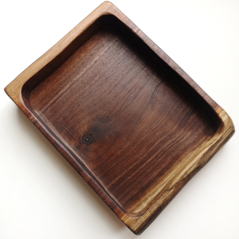 May include: A rectangular wooden tray with a dark brown finish. The tray has a smooth, polished surface and slightly rounded edges.