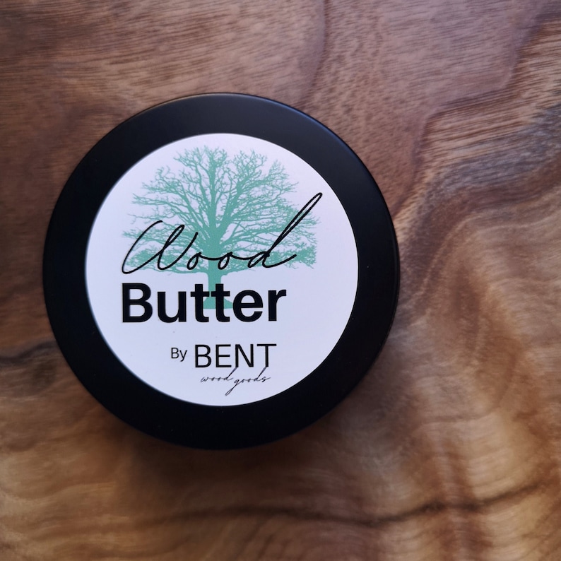 May include: A black jar with a white label that says "Wood Butter" and "By BENT wood goods". The label also features a green tree illustration.