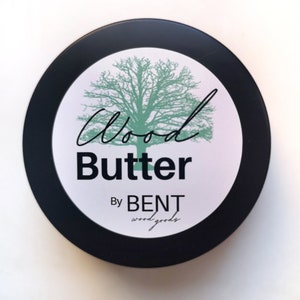 May include: A black round container with a white label that says "Wood Butter By BENT wood goods". The label also features a green tree illustration.
