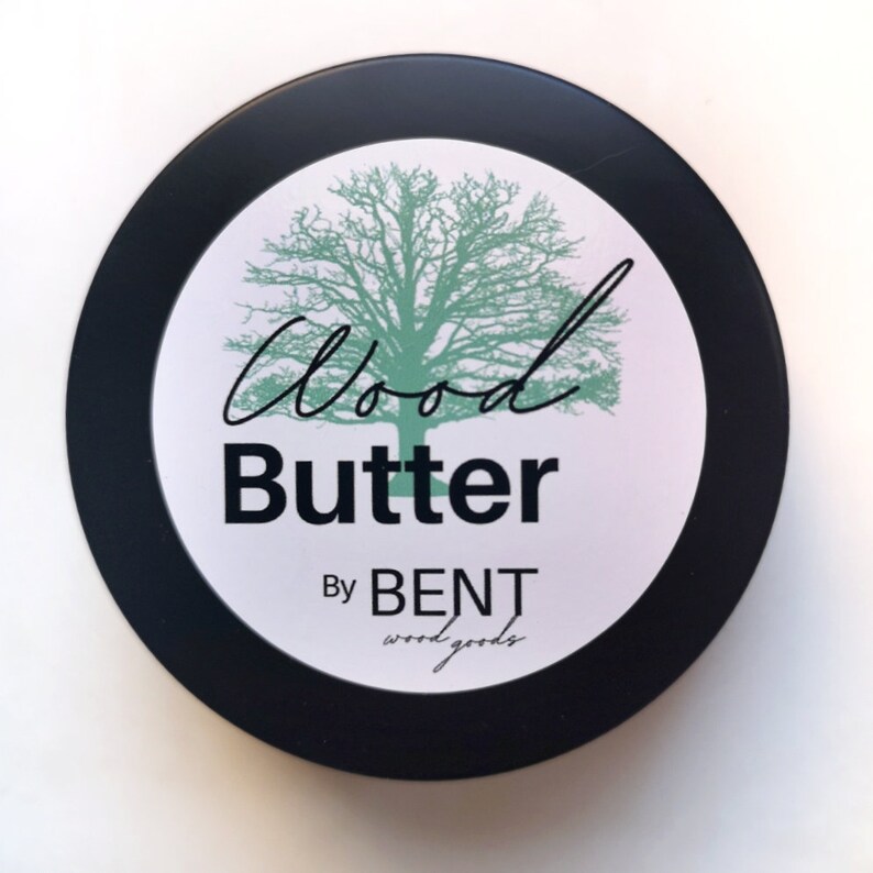 May include: A black round container with a white label that says "Wood Butter By BENT wood goods". The label also features a green tree illustration.