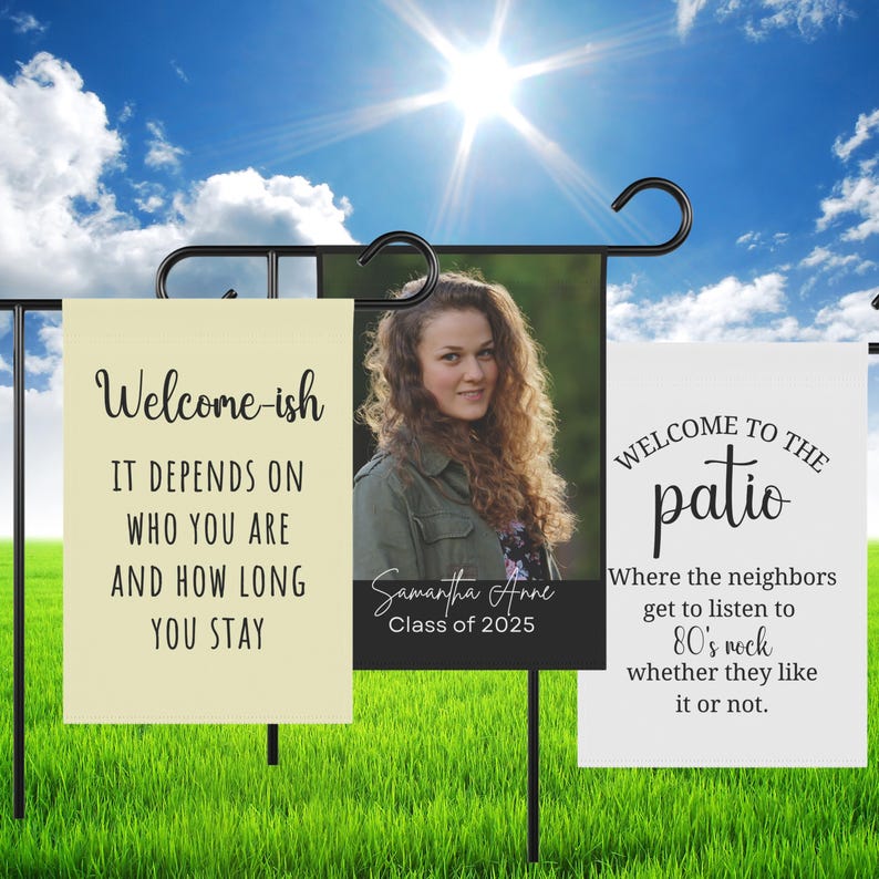 May include: Three rectangular garden flags on black metal stands. The left flag is cream with black text reading Welcome-ish IT DEPENDS ON WHO YOU ARE AND HOW LONG YOU STAY. The center flag features a portrait of a person with text Samantha Anne Class of 2025. The right flag is white with black text reading WELCOME TO THE patio Where the neighbors get to listen to 80's rock whether they like it or not.