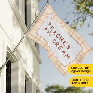 May include: A rectangular flag with a cream-colored background and a peach-colored plaid pattern. The flag features a white rectangle with the words "PEACHES AND CREAM" in brown. A flower graphic is in the upper left corner.