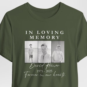 May include: Olive green t-shirt with the text "IN LOVING MEMORY" above three black and white photos. Below the photos is the name "David Reiner" and the years "1975-2025". The phrase "Forever in our hearts" is below.