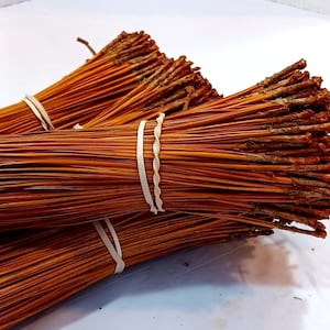 May include: A bundle of natural brown pine needles tied together with rubber bands. The needles are long and thin, and they are perfect for crafting or decorating.