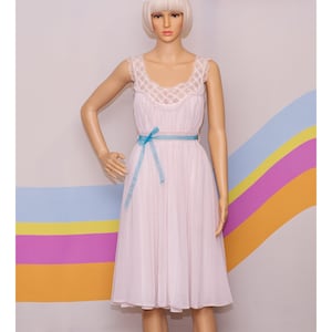 May include: Pale pink vintage dress with a square neckline and a blue ribbon belt. The dress features a lace trim on the neckline and a flowing skirt. The dress is displayed on a mannequin.