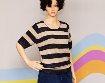 May include: A gold and navy blue striped short-sleeved sweater. The sweater features a scoop neckline and a ribbed hem. The gold stripes have a subtle shimmer. The garment is displayed on a mannequin.