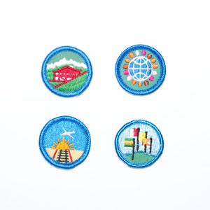 May include: Four embroidered patches with blue borders. One patch features a red building on a green hill. Another shows a globe surrounded by colorful shapes. The third depicts a plane and a train. The last one has colorful flags.