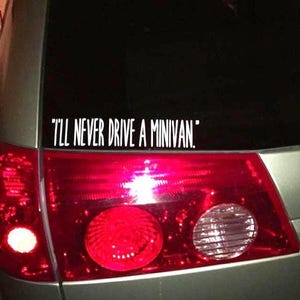 May include: A rear view of a silver minivan with a white sticker on the back window that reads "I'll never drive a minivan."