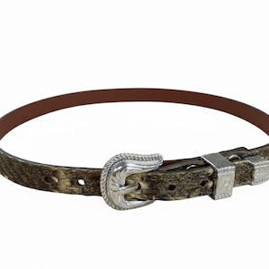 May include: A brown and tan belt with a silver buckle and accents. The belt has a textured pattern and a brown interior. The buckle is ornate with a floral design. The belt is approximately 1 inch wide.