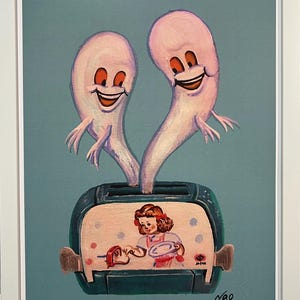 May include: A framed art print featuring a whimsical illustration. Two smiling, ghost-like figures emerge from a toaster, above a depiction of a girl. The artwork is set against a teal background, with the artist's signature and edition number visible.
