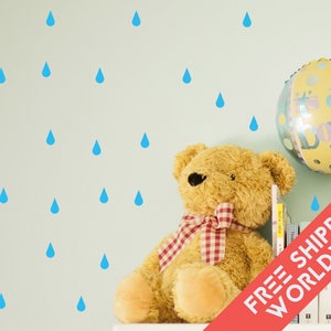 Peut inclure: Un mur bleu clair décoré d'autocollants en forme de gouttes de pluie bleues. Un ours en peluche avec un nœud à carreaux rouges et blancs est près d'un ballon avec l'inscription "It's a Boy".