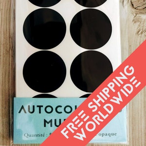 May include: A pack of black, circular stickers on a white background. The stickers are glossy and opaque. The package has text that reads "AUTOCOLLANT MU..." and "Quantité: 5".