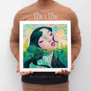 Puede incluir: Una impresión de 30,5 x 30,5 cm de una pintura digital que representa a una mujer con el pelo largo y negro sumergida en el agua. Los ojos de la mujer están cerrados y su rostro está pintado en una vibrante paleta de colores rosa y azul. El fondo es un suave degradado rosa y azul con nubes y vegetación verde.