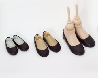 May include: Three pairs of black doll shoes with scalloped edges. The shoes are different sizes.