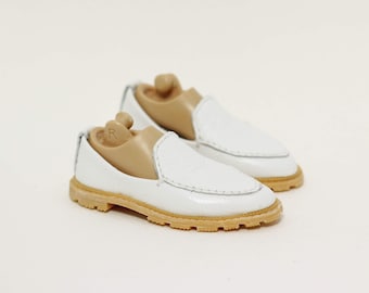 May include: A pair of white leather loafers with a brown rubber sole. The loafers have a slip-on design and are made of a soft, supple leather.