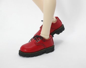May include: A pair of red leather doll shoes with black laces and a thick black sole.