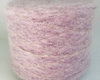 May include: A skein of soft, light pink yarn with a subtle shimmer. The yarn is wound into a ball shape and is ready for knitting or crocheting.