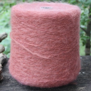 Op de afbeelding: Een bol zachte, pluche garen in een stoffige roze kleur. Het garen is gewikkeld rond een kartonnen buis.