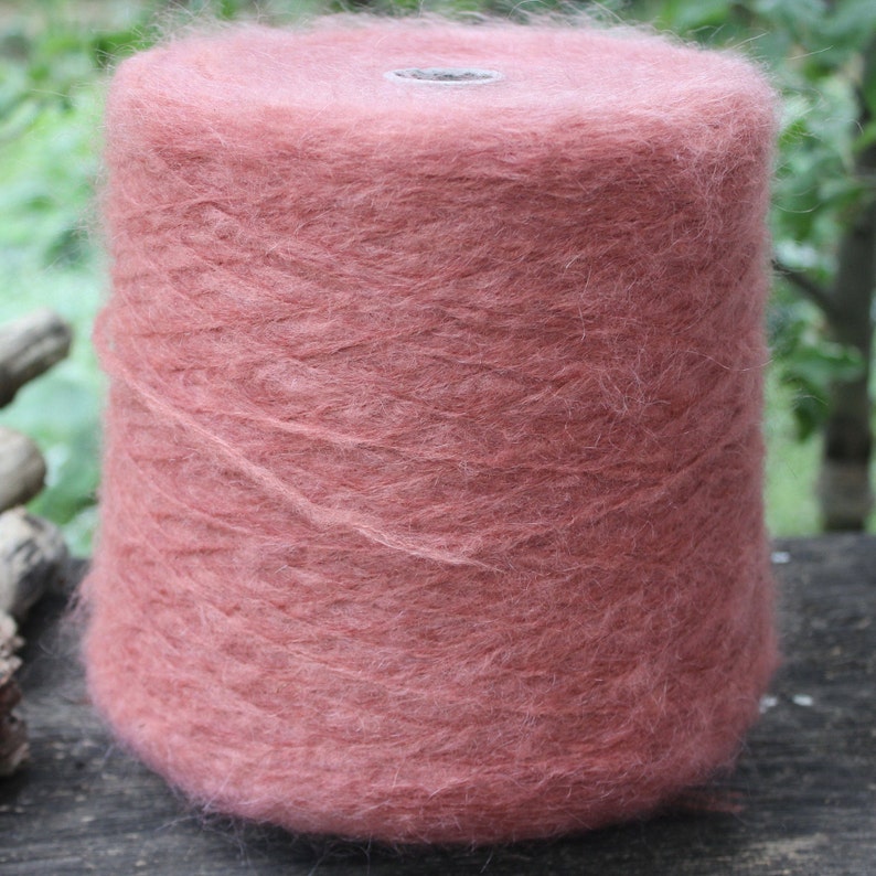 Op de afbeelding: Een bol zachte, pluche garen in een stoffige roze kleur. Het garen is gewikkeld rond een kartonnen buis.