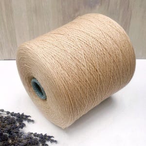 May include: A skein of beige yarn, wound into a ball shape. The yarn is soft and fluffy, and it would be perfect for knitting or crocheting.
