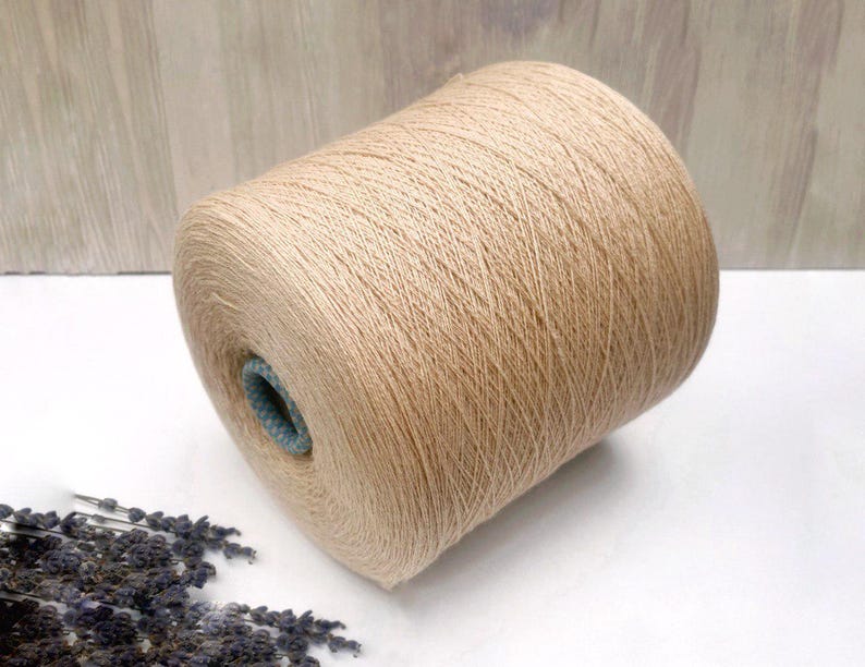 May include: A skein of beige yarn, wound into a ball shape. The yarn is soft and fluffy, and it would be perfect for knitting or crocheting.