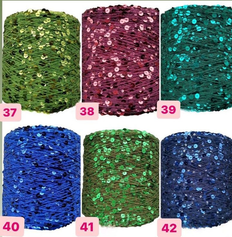 May include: Six spools of yarn with sequins woven into the yarn. The spools are arranged in two rows of three. The yarn colors are green, pink, teal, blue, dark green, and navy blue.