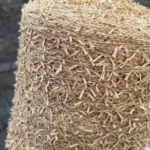 May include: A close-up of a skein of beige yarn with a fuzzy texture. The yarn is tightly wound and has a subtle sheen.