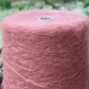 Op de afbeelding: Een close-up van een bol zachte, pluche garen in een stoffige roze kleur.