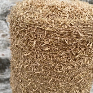 May include: Close-up of a beige yarn with a fuzzy texture. The yarn is tightly wound into a ball shape.
