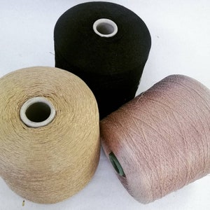 May include: Three spools of yarn in different colors: black, gold, and light brown.