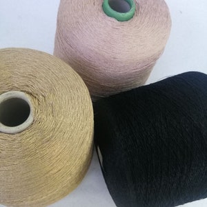 May include: Three spools of thread, one is black, one is gold, and one is a light pink color.