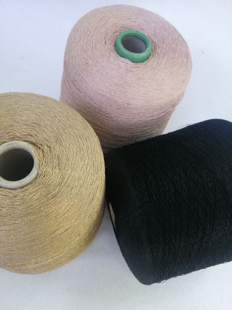May include: Three spools of thread, one is black, one is gold, and one is a light pink color.