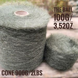 May include: Two balls of grey yarn, one cone-shaped and one ball-shaped, with the text "THE BALL 100G/3.52OZ" and "CONE 900G/2LBS". The yarn has a soft, fuzzy texture, suitable for knitting or crochet projects.