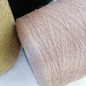 May include: Two spools of yarn, one gold and one light brown. The spools are wound with thread.