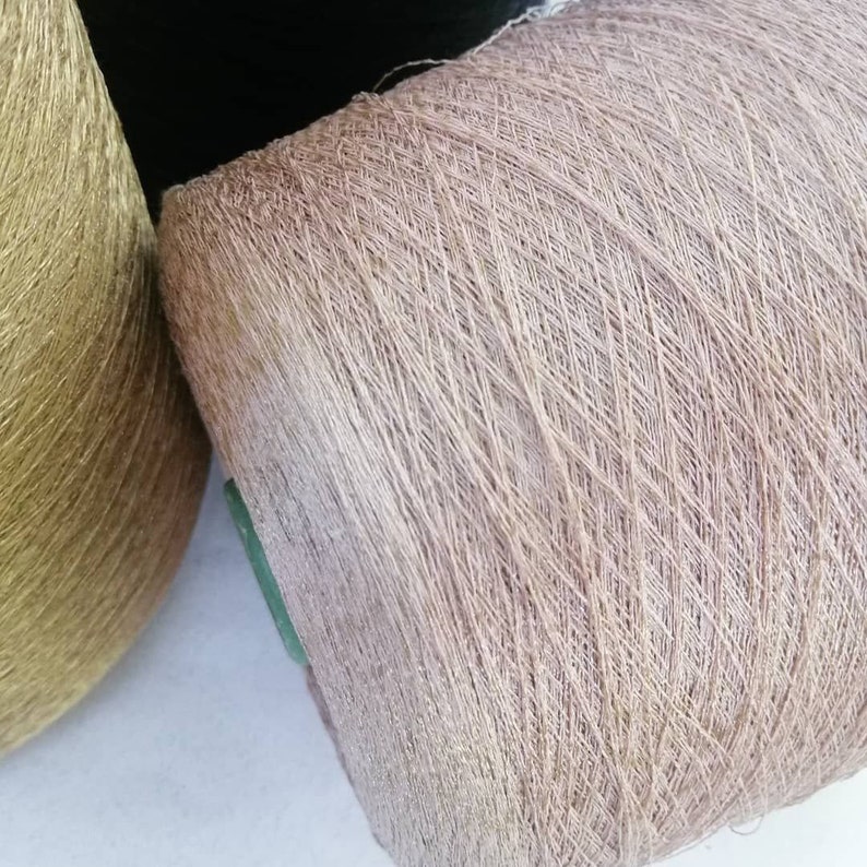 May include: Two spools of yarn, one gold and one light brown. The spools are wound with thread.