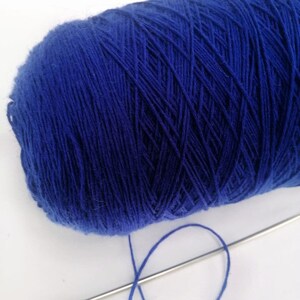 May include: A ball of deep blue yarn with a single strand of yarn extending from it.