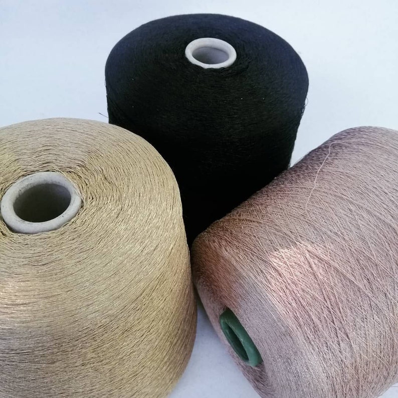 May include: Three spools of yarn in black, gold, and light brown.