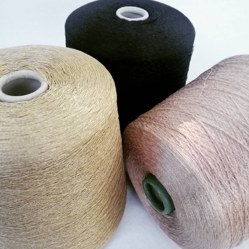 May include: Three spools of yarn in different colors: gold, black, and pink. The spools are made of a soft, textured material.