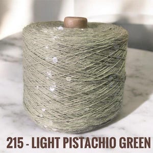 May include: A spool of light pistachio green yarn with silver sequins woven throughout.