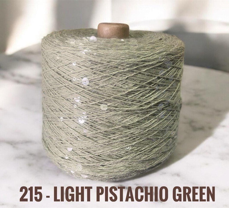 May include: A spool of light pistachio green yarn with silver sequins woven throughout.