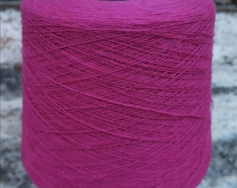 May include: A spool of deep pink yarn, wound tightly and ready for knitting or crocheting.