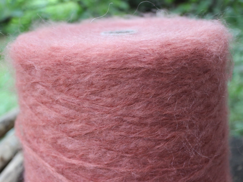Op de afbeelding: Een bol zachte, pluche garen in een stoffige roze kleur. Het garen is gewikkeld rond een kartonnen buis.