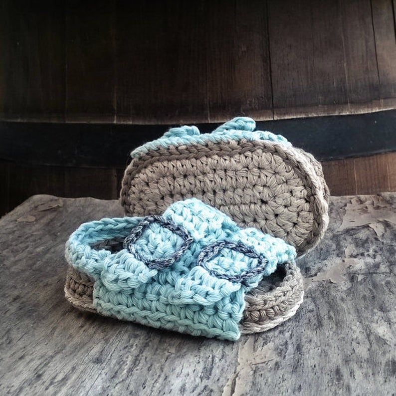 Op de afbeelding: Een paar gehaakte babysandalen in lichtblauw en bruin. De sandalen hebben een simpel ontwerp met een bandje over de bovenkant en een klein gespje.